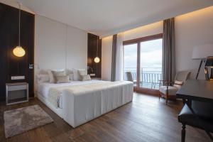 a bedroom with a large white bed and a balcony at Hotel Santa Marta in Lloret de Mar