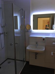 La salle de bains est pourvue d'un lavabo, d'un miroir et d'une douche. dans l'établissement Hotel Stadt Magdeburg, à Perleberg