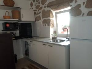 a kitchen with a white refrigerator and a sink at Casinha de Lamares in Vila Real