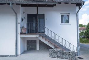 ein weißes Haus mit einer Treppe und einem Balkon in der Unterkunft Ferienwohnungen Mildenberger in Birkenau
