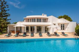 Villa con piscina con sillas y sombrillas. en Villa Rocamar en Cala en Blanes