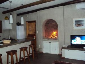 a kitchen with a fireplace and a bar with stools at Kalahari Cottage in Askham
