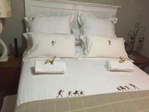 Una cama con almohadas blancas con caballeros. en Kalahari Cottage, en Askham