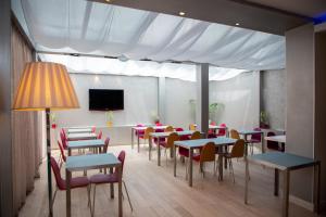 Appart Hôtel Clément Ader في تولوز: غرفة طعام مع طاولات وكراسي وتلفزيون