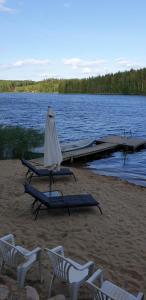 a group of chairs and tables on a beach with a dock at Tilhi 1 Cottage in Piojärvi