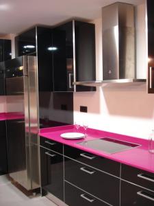 eine Küche mit einer rosa Arbeitsplatte und schwarzen Schränken in der Unterkunft Albergue Revolutum Hostel in Salamanca