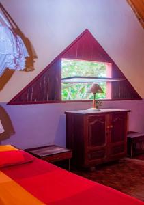 a attic room with a bed and a window at Reva Castel in Nosy Be