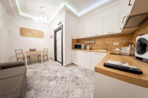 ソフィアにあるSofia Pearl Life Apartment - No Window Apartmentの白いキャビネット、ソファ、テーブル付きのキッチンが備わります。