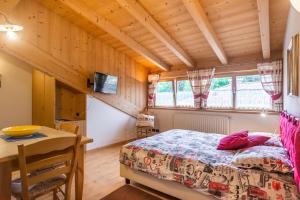 ein Schlafzimmer mit einem Bett und einem Tisch in einem Zimmer in der Unterkunft Holiday Apartments Val Moena in Cavalese