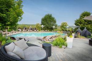 a swimming pool with a wicker chair next to at Estrimont Suites & Spa in Magog-Orford