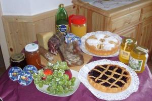 einen Tisch mit Kuchen und Obst auf einem lila Tischtuch in der Unterkunft Agritur Due Valli in Livo