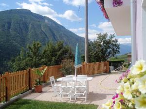 eine Terrasse mit Stühlen und einem Tisch mit einem Sonnenschirm in der Unterkunft Agritur Due Valli in Livo