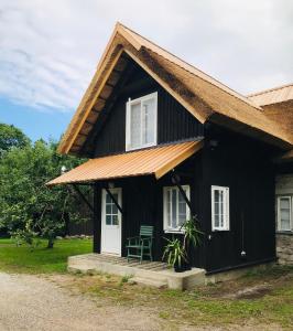 una casa negra con una puerta blanca y una silla verde en Jurna Recreation Farm, en Upa