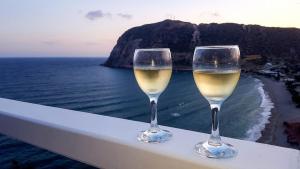 two glasses of white wine sitting on a ledge overlooking the ocean at Agia Kyriaki Studios in Agia Kiriaki Beach
