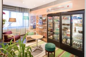 a store with a refrigerator and a table and chairs at Novotel Suites Clermont Ferrand Polydome in Clermont-Ferrand