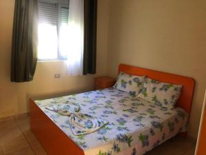 a bedroom with a bed with a floral bedspread and a window at Beachside Apartments Smajlaj in Velipojë