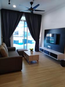 a living room with a couch and a flat screen tv at The Wave Residence in Malacca