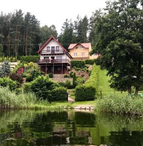 uma casa numa colina ao lado de um lago em Wakacyjny Hartowiec - dom nad brzegiem jeziora em Grodziczno