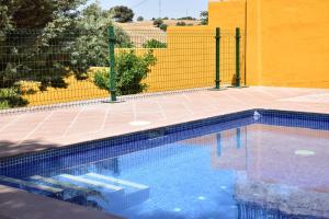 una piscina frente a una valla amarilla en CASA CAPELLANIA-chalet con piscina junto a Madrid, en Méntrida