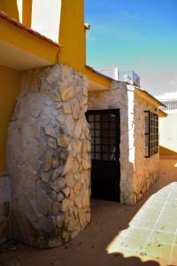 un edificio de piedra con puerta y pared de piedra en CASA CAPELLANIA-chalet con piscina junto a Madrid, en Méntrida
