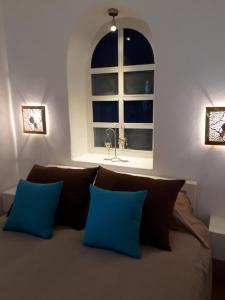 een bed met twee blauwe kussens voor een raam bij Dar es Salam-Baja in Asilah