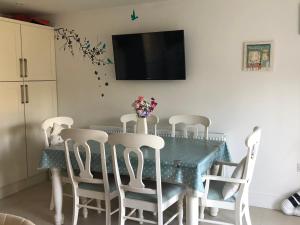 uma mesa de jantar com cadeiras e uma televisão na parede em Buckfield Roost 3 bedroom Newlyn, free parking for 2 cars em Newlyn