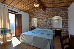 a bedroom with a bed and a stone wall at Hotel Goloritzé in Baunei