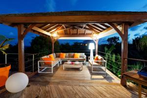 a wooden pergola with a couch and chairs on a deck at Villa Kouleur Kafé in Sainte-Anne