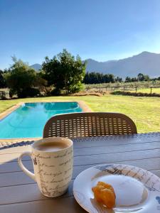 a cup of coffee and a plate of food on a table at The Barn in Franschoek in Franschhoek