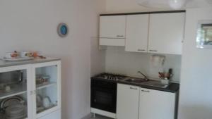 a kitchen with white cabinets and a stove top oven at Villa del Palmeto in Badesi