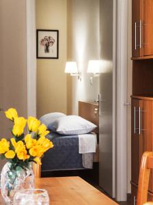 a small room with a bed and a vase of yellow flowers at Garden House near the sea in Kavala