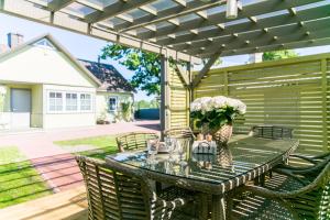 un patio con una mesa con sillas y una pérgola en Viigi Villa en Haapsalu