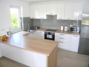 a kitchen with white cabinets and a wooden counter top at Apartmani Krajinovic in Krk