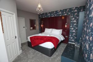 a bedroom with a large bed with a red blanket at The Stamford in Southport