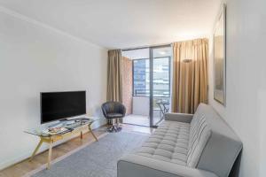 a living room with a couch and a television at Santa Magdalena Apartments in Santiago