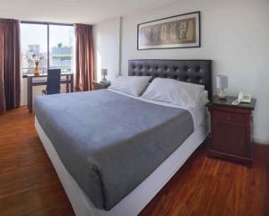 een slaapkamer met een groot bed en een bureau met een telefoon bij Santa Magdalena Apartments in Santiago