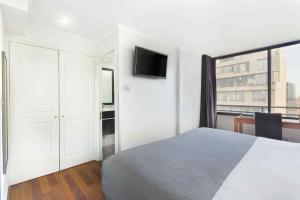 a white bedroom with a bed and a window at Santa Magdalena Apartments in Santiago