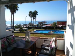 taras ze stołem i krzesłami oraz basenem w obiekcie Precioso apartamento en primera línea de playa de la Barrosa w mieście Chiclana de la Frontera