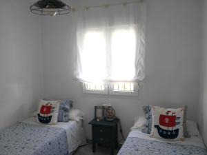 sypialnia z dwoma łóżkami i oknem w obiekcie Precioso apartamento en primera línea de playa de la Barrosa w mieście Chiclana de la Frontera