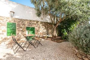 a table and chairs in front of a stone building at Oliveira Surf House Ericeira in Santo Isidoro