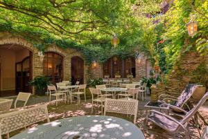 eine Außenterrasse mit Tischen, Stühlen und Reben in der Unterkunft Hôtel Sainte Foy in Conques