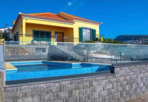 eine Villa mit einem Pool vor einem Haus in der Unterkunft Villa Sunrise View by Madeira Sun Travel in Santa Cruz