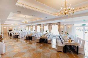 a banquet hall with tables and chairs and a chandelier at Hotel Korczowa in Młyny