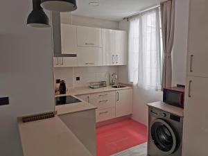 a kitchen with white cabinets and a washing machine at Begoña 18 Rest & Adventure in Gijón
