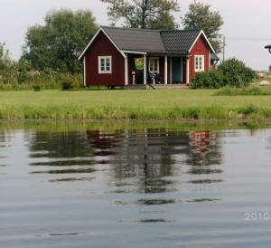 ein rotes Haus am Wasser in der Unterkunft Svalsjöns Stugor Öland in Köpingsvik