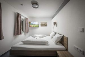een slaapkamer met een bed met witte lakens en kussens bij Kaiserwinkl Apartments Daxer in Walchsee