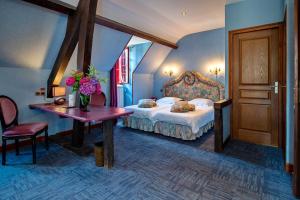Un dormitorio con una cama y una mesa con flores. en Hôtel Sainte Foy, en Conques