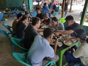 Eine Gruppe von Menschen, die an Tischen sitzen und Essen essen. in der Unterkunft Iboih Malini Bungalow in Sabang