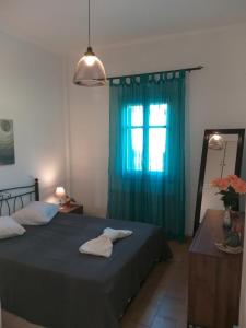 a bedroom with a bed with a blue curtain and a window at Nikolettas Apartments in Faros