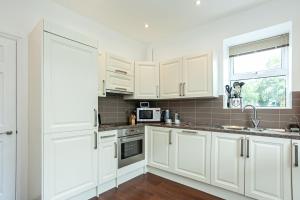 凯西克Carlton 2 a large modern Keswick appt with parking的白色的厨房配有白色的橱柜和微波炉